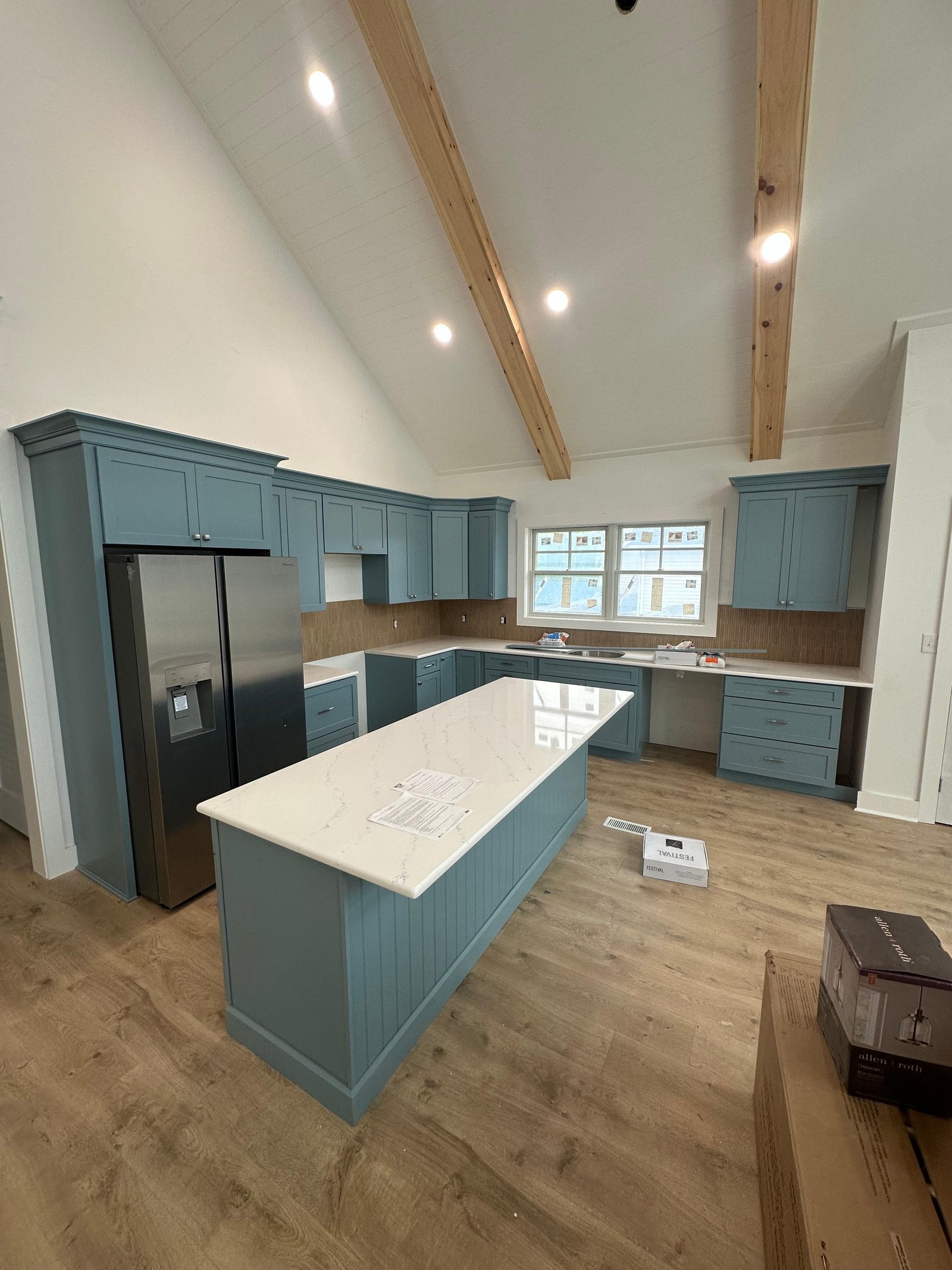 Completed blue kitchen cabinetry with island countertop and appliances